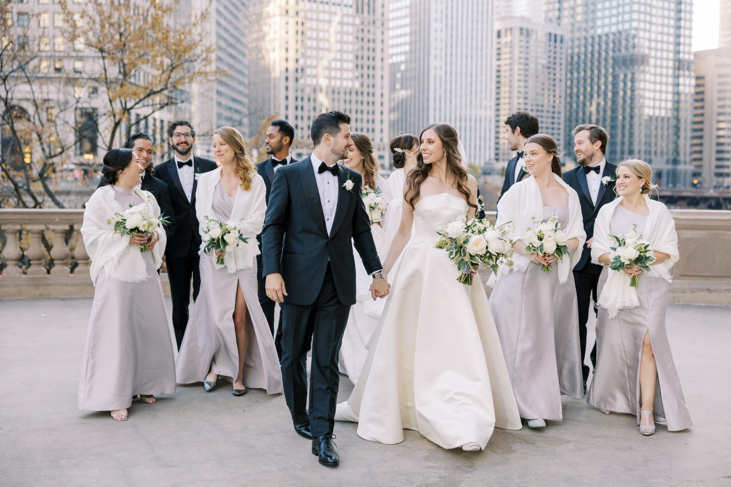 Bride and groom walking with their bridal party in downtown Chicago, planned by Chicago wedding planner Savoir Fête. The Blackstone Hotel wedding highlights elegance and joy.