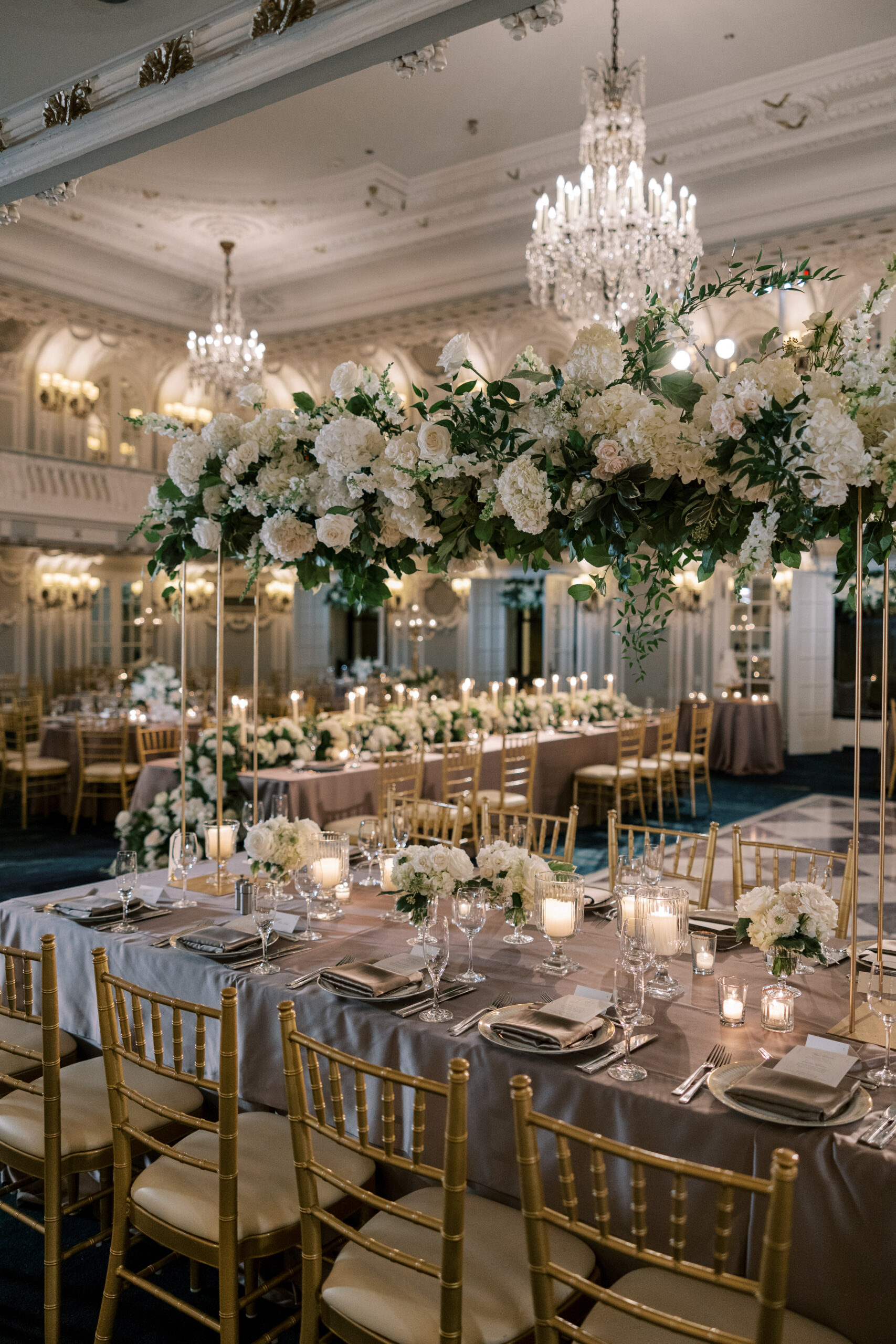 Elegant reception tables with gold chairs, floral centerpieces, and candlelight at the Blackstone Hotel, featuring lush overhead arrangements. Designed by Chicago wedding planner Savoir Fête.
